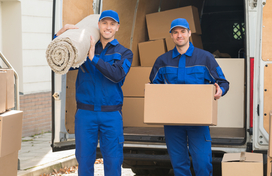 Two moving men holding a rug and a box in front of a moving truck