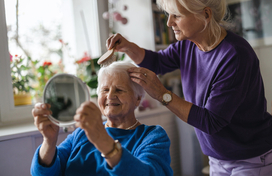 A person brushes an older adult's hair 
