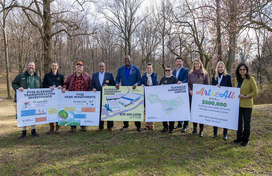 A photo of County Executive and attendees holding up signs outlining his proposed Fiscal Year 2026 budget investments for Elkridge.