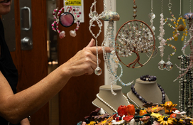 Handcrafted beaded art hanging with a person touching one of the items