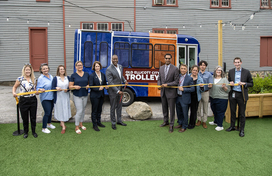 A photo of County Executive Calvin Ball and attendees preparing to cut the ribbon on the County's new pilot Old Ellicott City Trolley.
