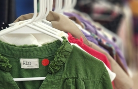 Clothes hanging on rack with hangers. First item is olive green shirt.