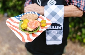 Person holding a plate with a open faced hamburger on it