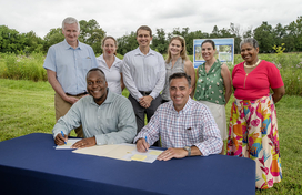A photo of County Executive Calvin Ball and Columbia Association (CA) President and CEO Shawn MacInnes getting read to sign a Memorandum of Understanding to enhance collaboration between the County and CA and strengthen local action on climate and energy independence.