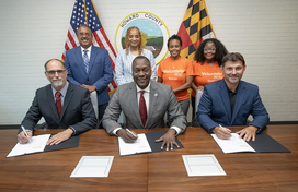 A photo of County Executive Calvin Ball with Lincoln College of Technology President Dr. James Martin and County Department of Recreation & Parks’ Director Nick Mooneyhan seated at a table and getting ready to sign a Memorandum of Understanding to formalize an innovative collaboration to expand Recreation & Parks’ Service & Skills Club’s service-learning workshops.