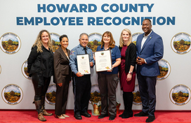 A photo of County Executive Calvin Ball and Howard County Government leaders with the County's 2025 Employee of the Year Genevieve LaPorte from the Howard County Police Department.