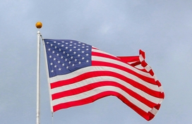 American flag on flag pole outside with sky in the background