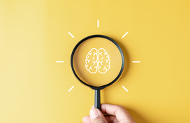 Drawing of a brain with a magnifying glass over top on a bright yellow background.