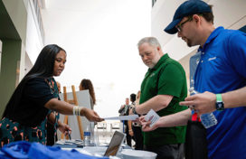 An Office of Workforce Development employee speaking to two attendees at a job fair, handing them an informative flyer.