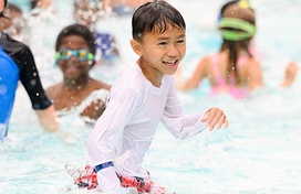 Smiling boy playing in pool with water splashing around
