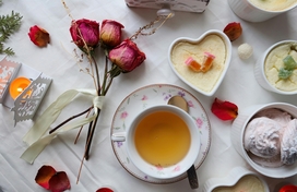 Dried roses, cup of tea and desserts on a table.