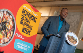 A photo of County Executive Calvin Ball speaking at the podium during the press conference announcing the launch of the 2026 winter season's Howard County Restaurant & Craft Beverage Weeks.