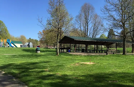 Wide shot of park with a picnic pavilion, blue sky, and green grass