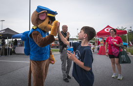 A person dressed as Chase from Paw Patrol high fives a child at National Night Out