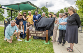 County Executive Calvin Ball and others pulling off the cover to unveil the new Grace Kubofcik Bocce Courts sign at Cedar Lane Park West.