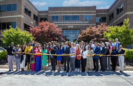 County Executive Calvin Ball posed out front of the County's new Opportunity and Economic Mobility Center at 9755 Patuxent Woods Drive in Columbia, holding scissors and surrounded by event attendees as he gets ready to cut the yellow ribbon opening the building.