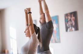 man and woman stretching with arms raised towards ceiling