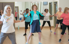 Group of women participating in fitness class inside.