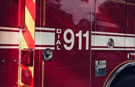red emergency responder vehicle with white stripes and white font displaying "Dial 911"