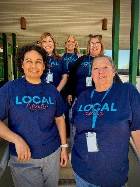 Five Health Department Community Health Workers wearing blue t-shirts standing outside the Health Department building on the steps