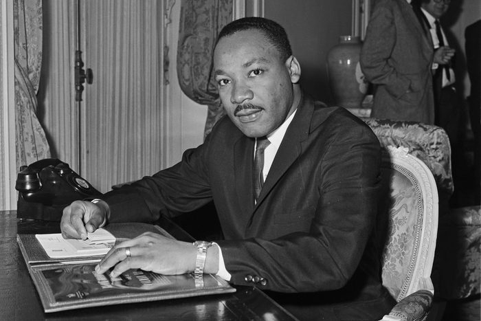 A photograph of Dr. Martin Luther King, Jr. seated at desk