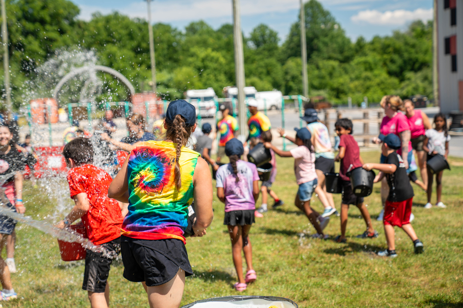 Campers and counselors use buckets of water to splash each other and cool off in the heat.