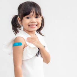 Young girl with pigtails shows the band-aid on her upper arm