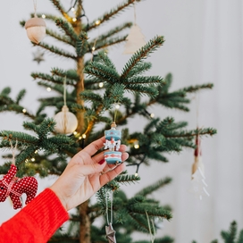 Arm reach out and touching ornament on a Christmas tree.