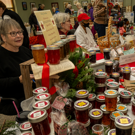 Craft items and jams on a table with vendors selling.