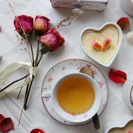 Dried roses, cup of tea and desserts on a table.