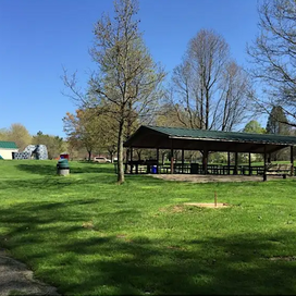 Wide shot of park with a picnic pavilion, blue sky, and green grass