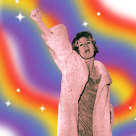 An image still of a trans woman in a pink faux fur coat with her fist extended over her head on a rainbow background. 