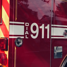 red emergency responder vehicle with white stripes and white font displaying "Dial 911"